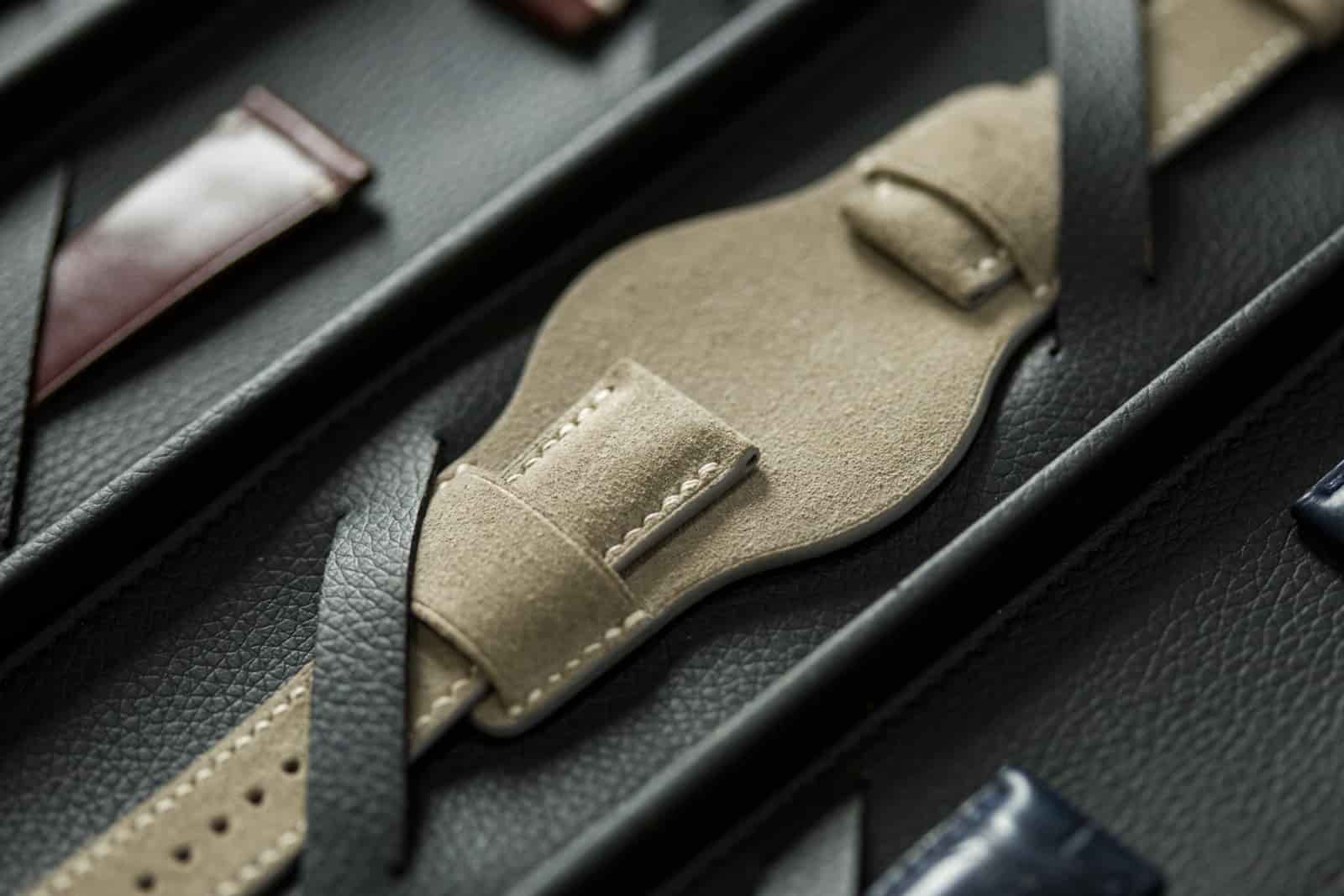 Close view into the sample box showing a suede bund pad and stitched leather straps, the brushed nap and burnished edges legible