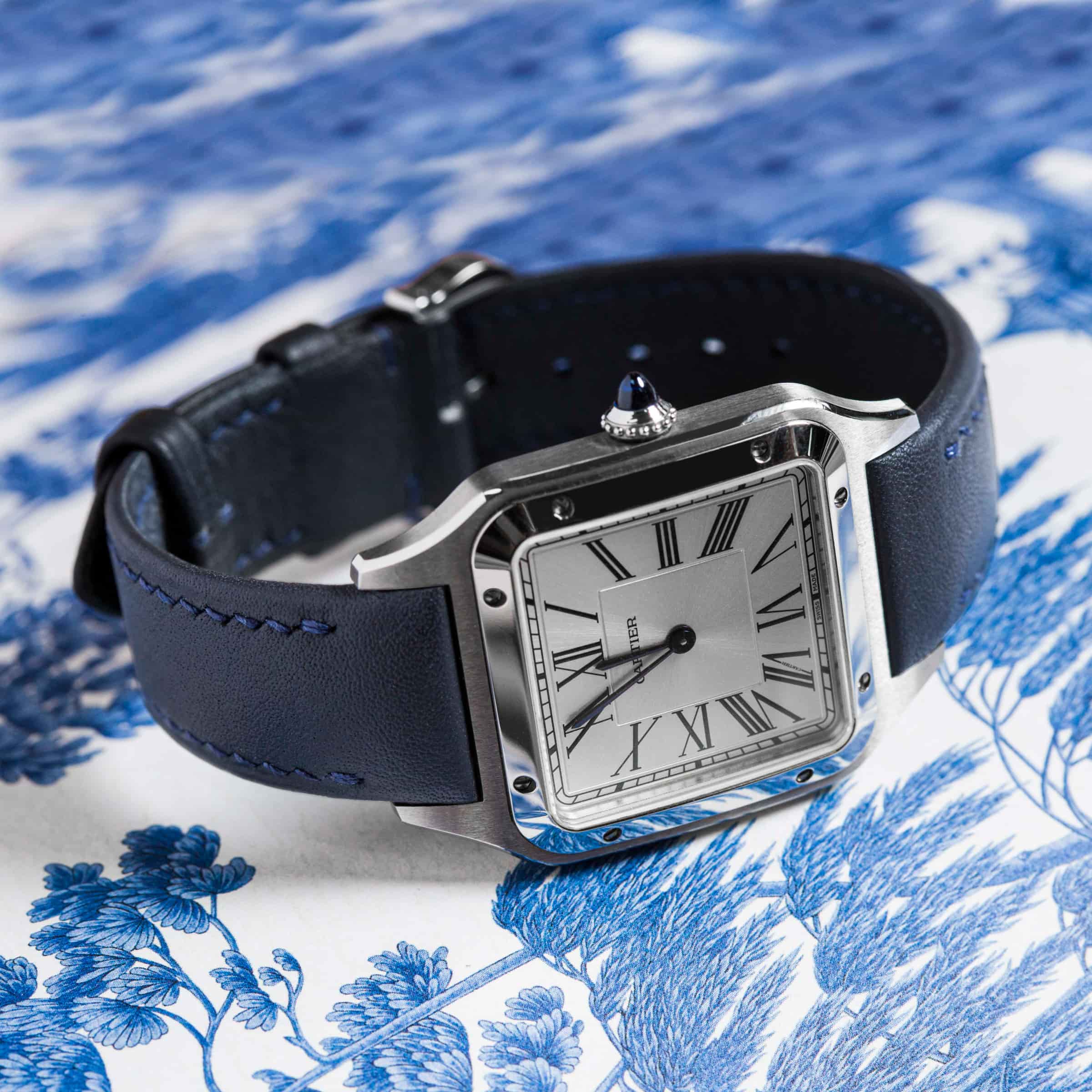 Navy calf leather strap fitted to a steel square-cased watch with a Roman-numeral dial, photographed on blue-and-white porcelain